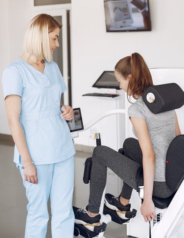 young-woman-doing-exercises-simulator-with-therapist-gym (1)